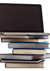 Photo of laptop on pile of books.
